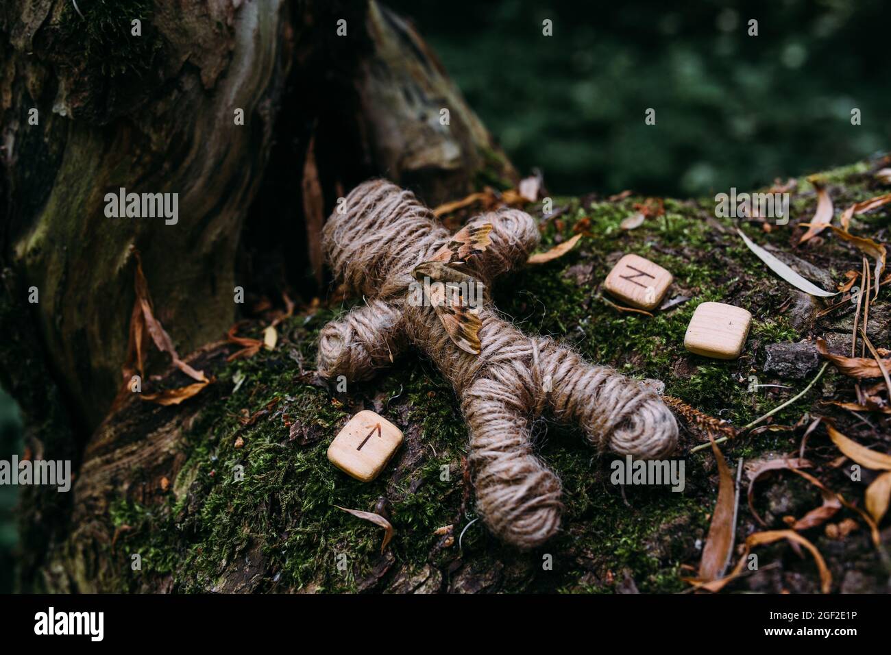 Una bambola voodoo intrecciata di fili, falce e rune in rituale nella foresta misteriosa. Foto Stock
