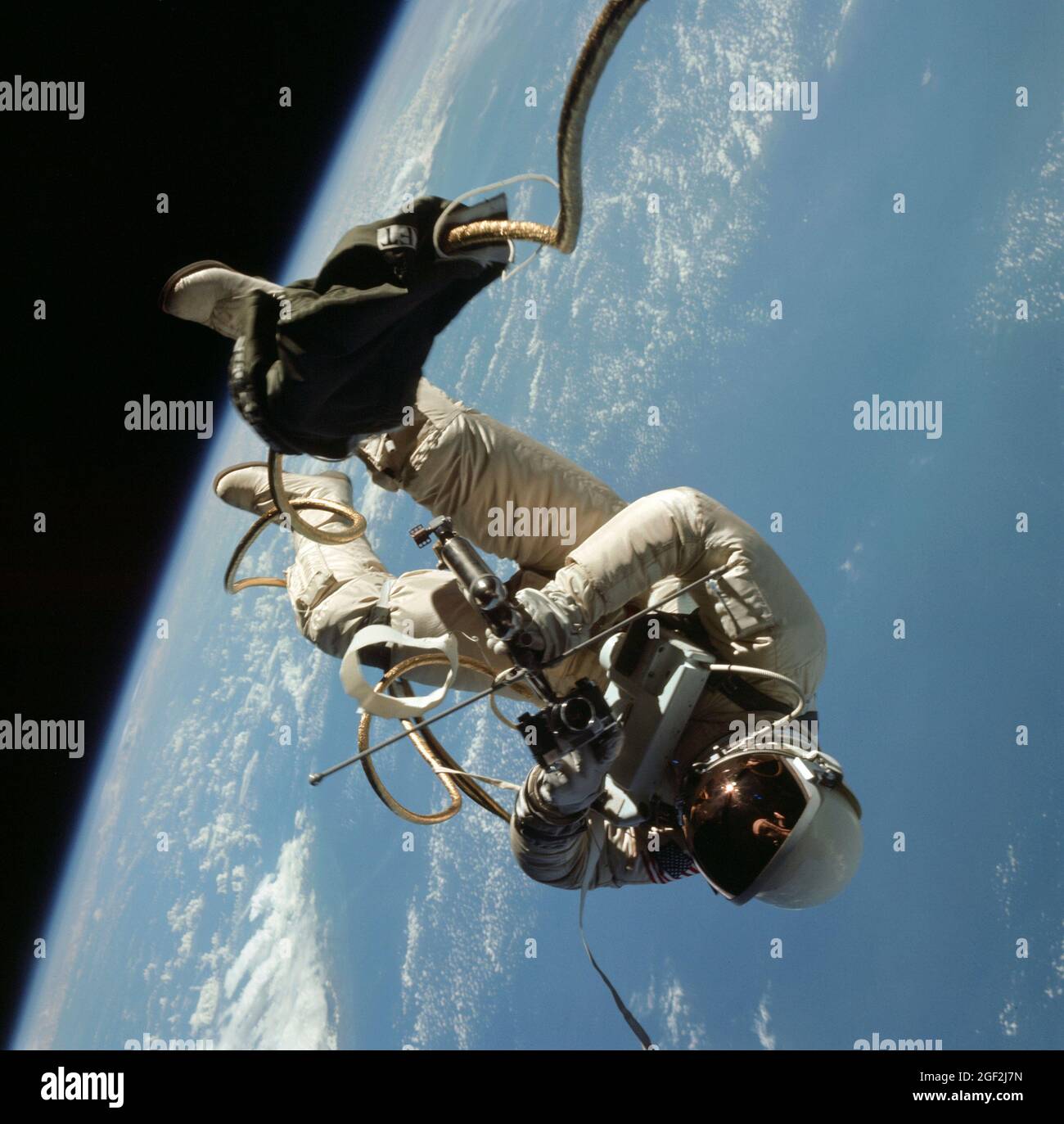 (3 giugno 1965) --- l'astronauta Edward H. White II, pilota della missione orbitale terrestre di quattro giorni di Gemini IV, galleggia nella gravità zero dello spazio al di fuori della navicella spaziale Gemini IV. Il bianco indossa una tuta spaziale appositamente progettata; e la visiera del casco è placcata oro per proteggerlo dai raggi del sole non filtrati. Indossa anche un pacco di ossigeno di emergenza. È assicurato alla navicella spaziale da una linea ombelicale di 25 piedi e da una linea di ancoraggio di 23 piedi, entrambi avvolti in nastro d'oro per formare un cordone. Nella sua mano destra c'è un'unità di manovra automatica (HHSMU) con cui controlla i suoi movimenti nello spazio Foto Stock