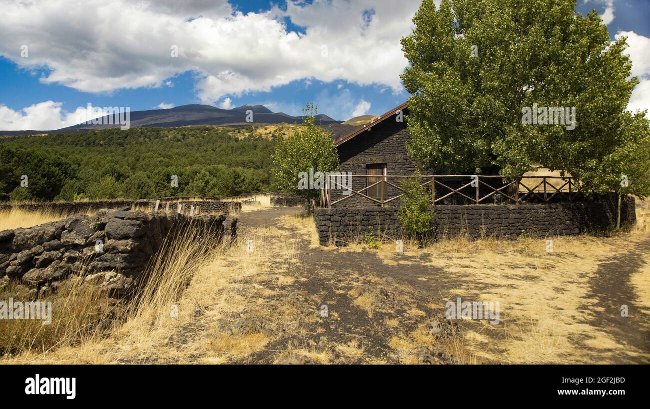 Paesaggio del vulcano Etna con rifugio e vista del cratere durante le giornate di sole e cielo blu con nuvole. Foto Stock