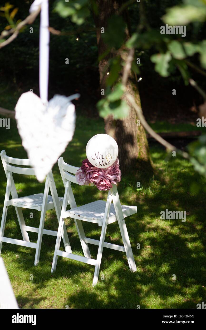 sedie per matrimoni, disposte in file all'esterno del parco, con decorazioni artigianali. Foto di alta qualità Foto Stock