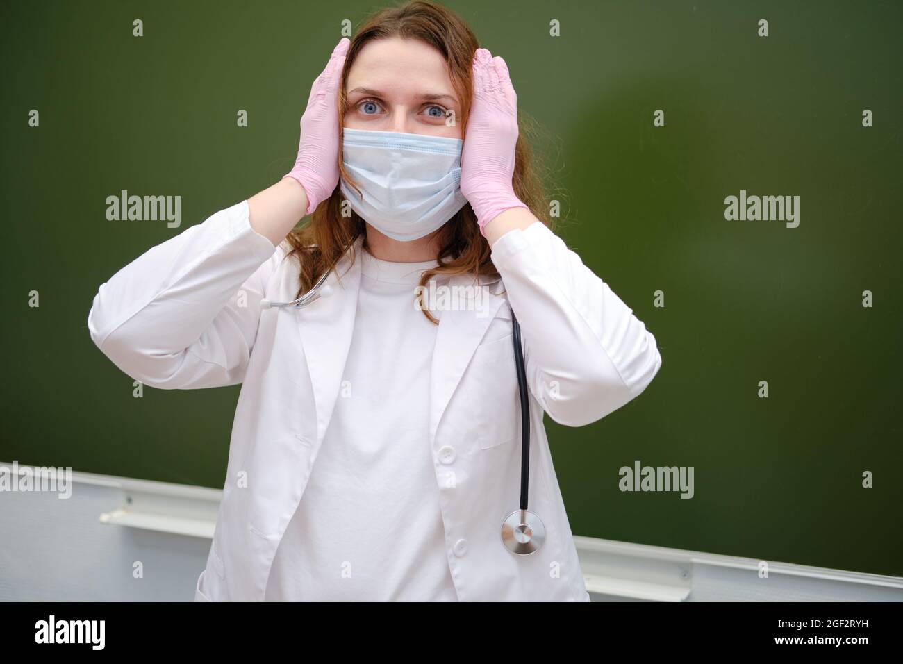 Medico spaventato in maschera medica in classe scolastica. Concetto di problemi a scuola durante l'epidemia di coronavirus Foto Stock