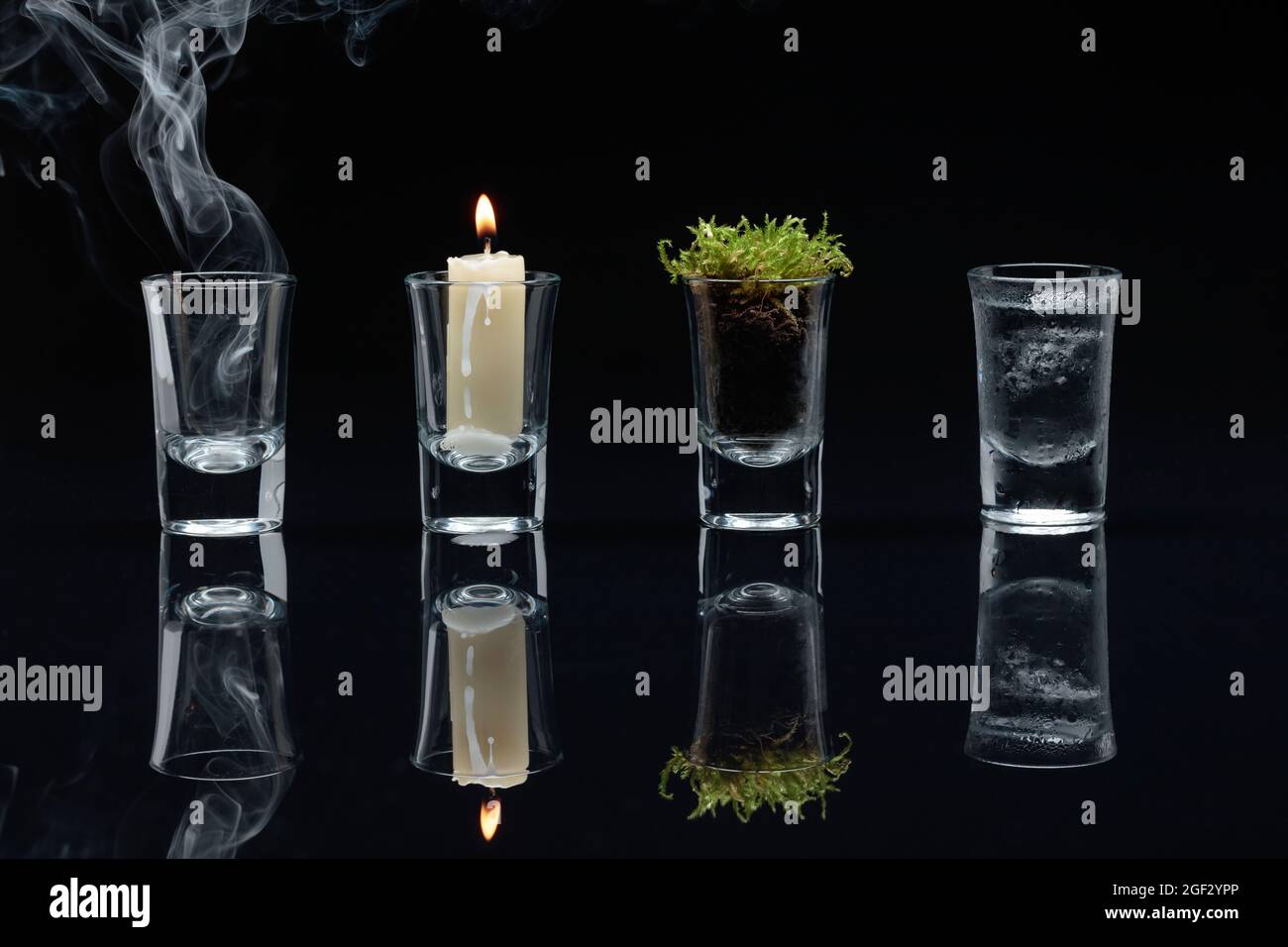 Quattro elementi della natura: Aria, fuoco, terra, acqua. Quattro elementi di concetto in occhiali su uno sfondo nero riflettente. Foto Stock