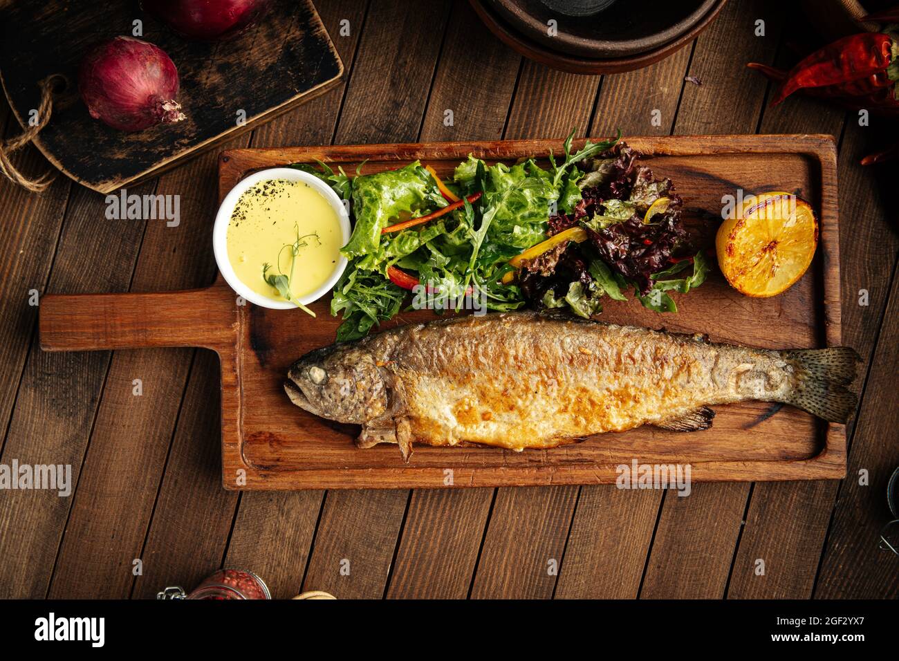 Pesce di trota fritto fatto in casa con salsa e insalata Foto Stock