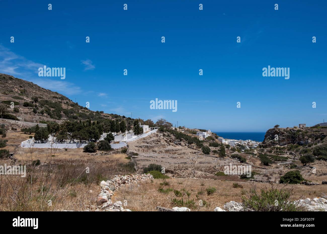 Isola di Kimolos, Chora, Cicladi Grecia. Cimitero presso il cimitero, lontano dal muro bianco del villaggio intorno alle lapidi. Edifici bianchi di calma della città Foto Stock