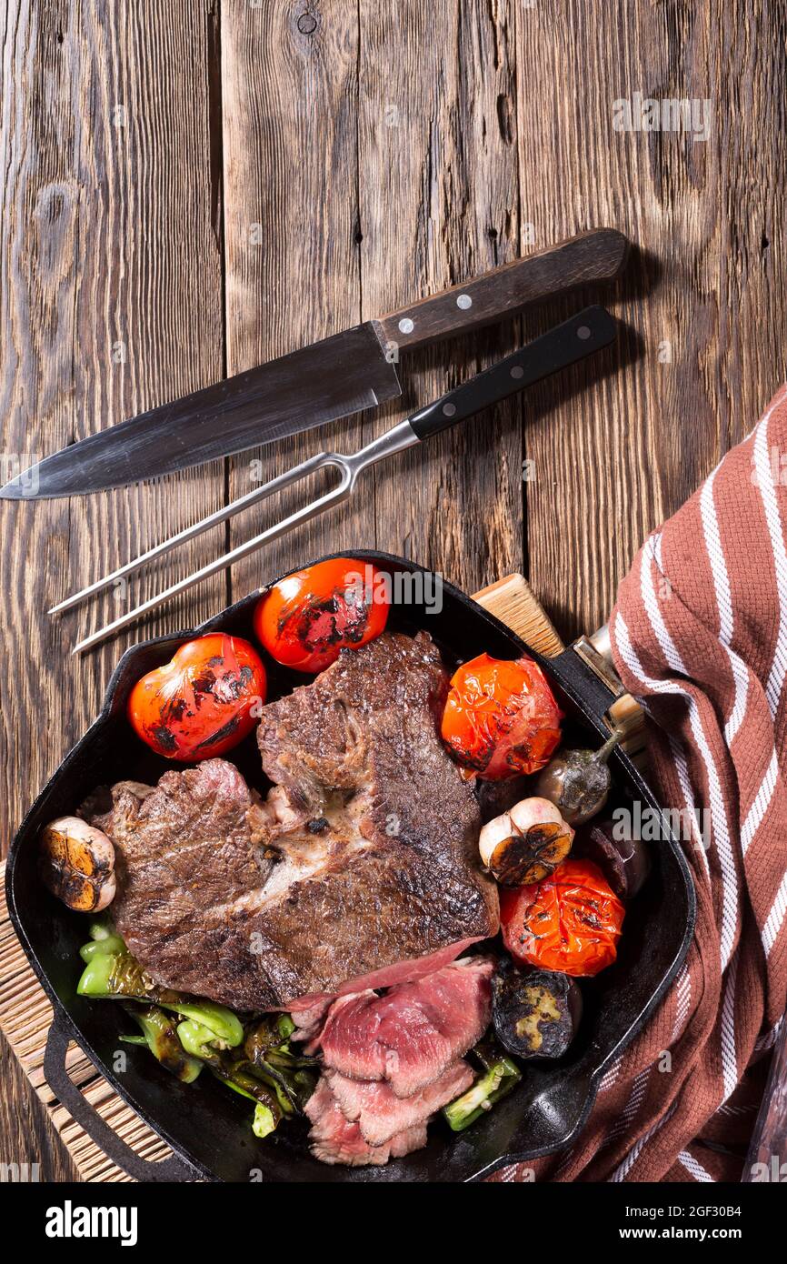 Un pezzo di carne alla griglia in una padella di ghisa con verdure, primo  piano Foto stock - Alamy
