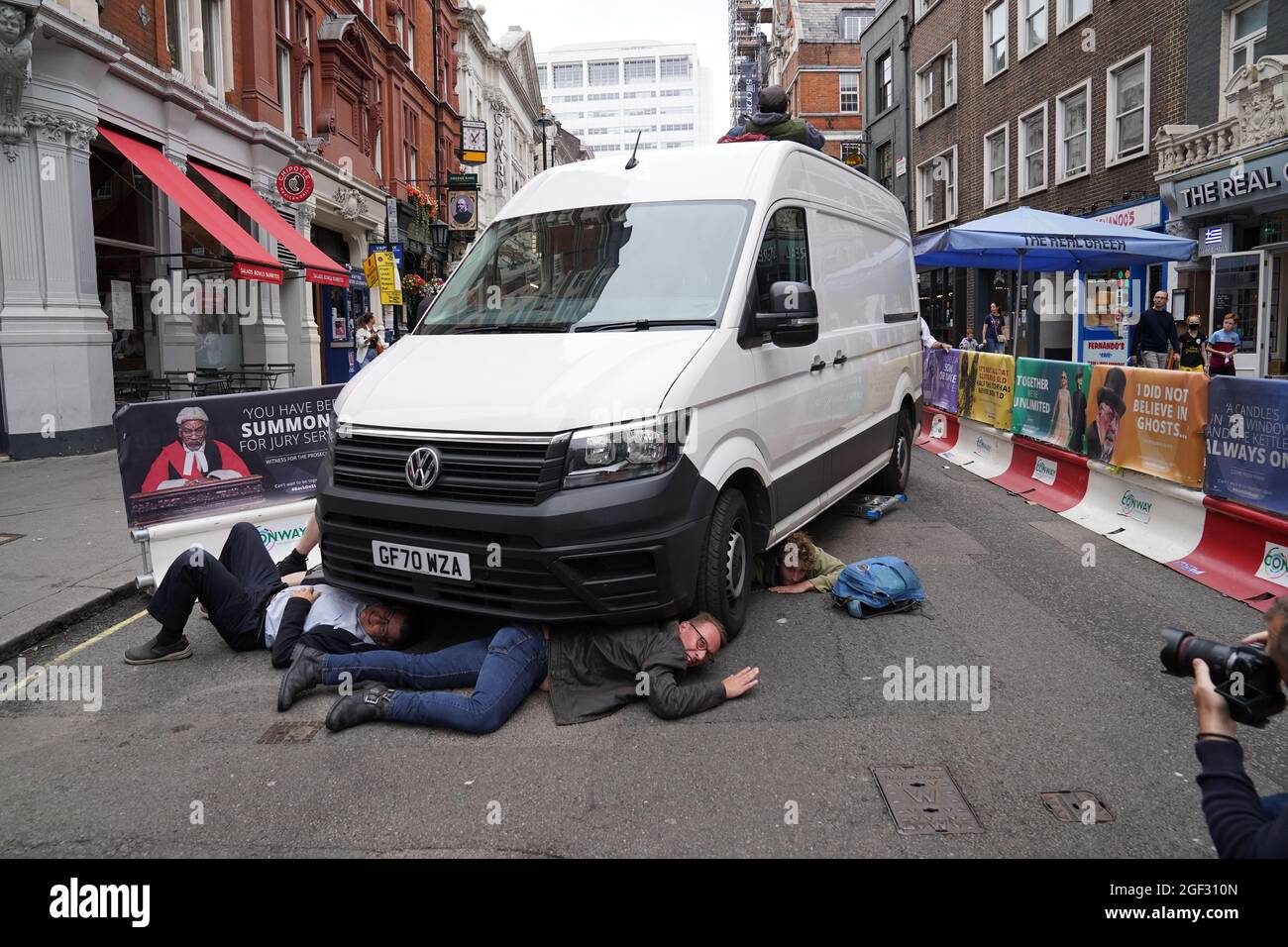 I dimostranti si posizionano sotto un furgone durante una protesta dei membri della ribellione di estinzione vicino a Covent Garden, nel centro di Londra, all'inizio di due settimane di azione previste dal gruppo di protesta per il cambiamento climatico. Data foto: Lunedì 23 agosto 2021. Foto Stock