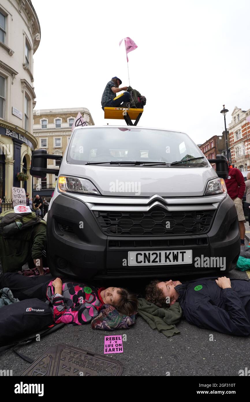 I dimostranti si posizionano sotto un furgone durante una protesta dei membri della ribellione di estinzione vicino a Covent Garden, nel centro di Londra, all'inizio di due settimane di azione previste dal gruppo di protesta per il cambiamento climatico. Data foto: Lunedì 23 agosto 2021. Foto Stock