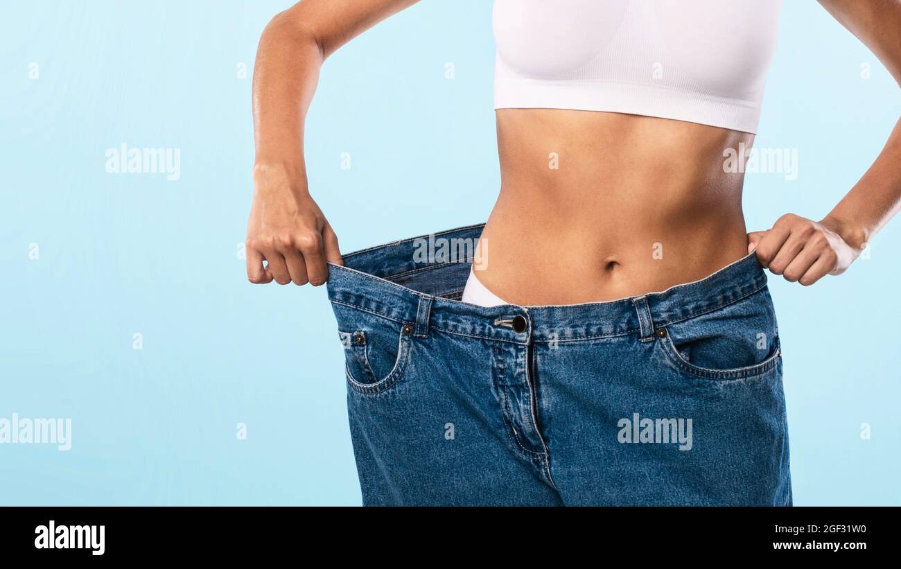 Primo piano di Skinny Fit Donna tirando grandi jeans sciolti Foto Stock