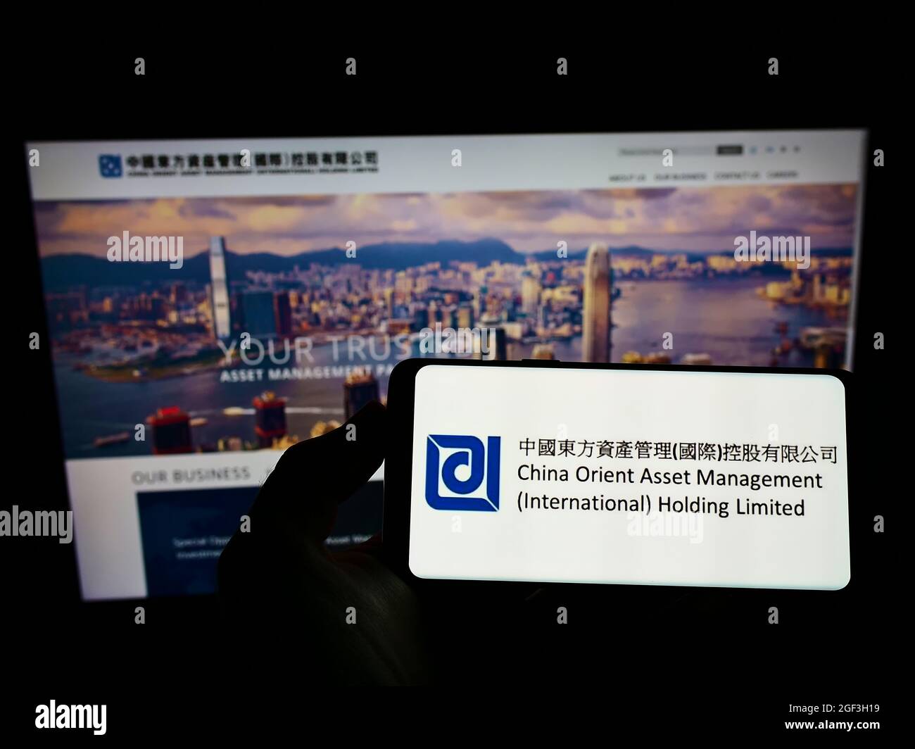 Persona che tiene smartphone con il logo della società China Orient Asset Management Co. Ltd. Sullo schermo di fronte al sito Web. Mettere a fuoco sul display del telefono. Foto Stock