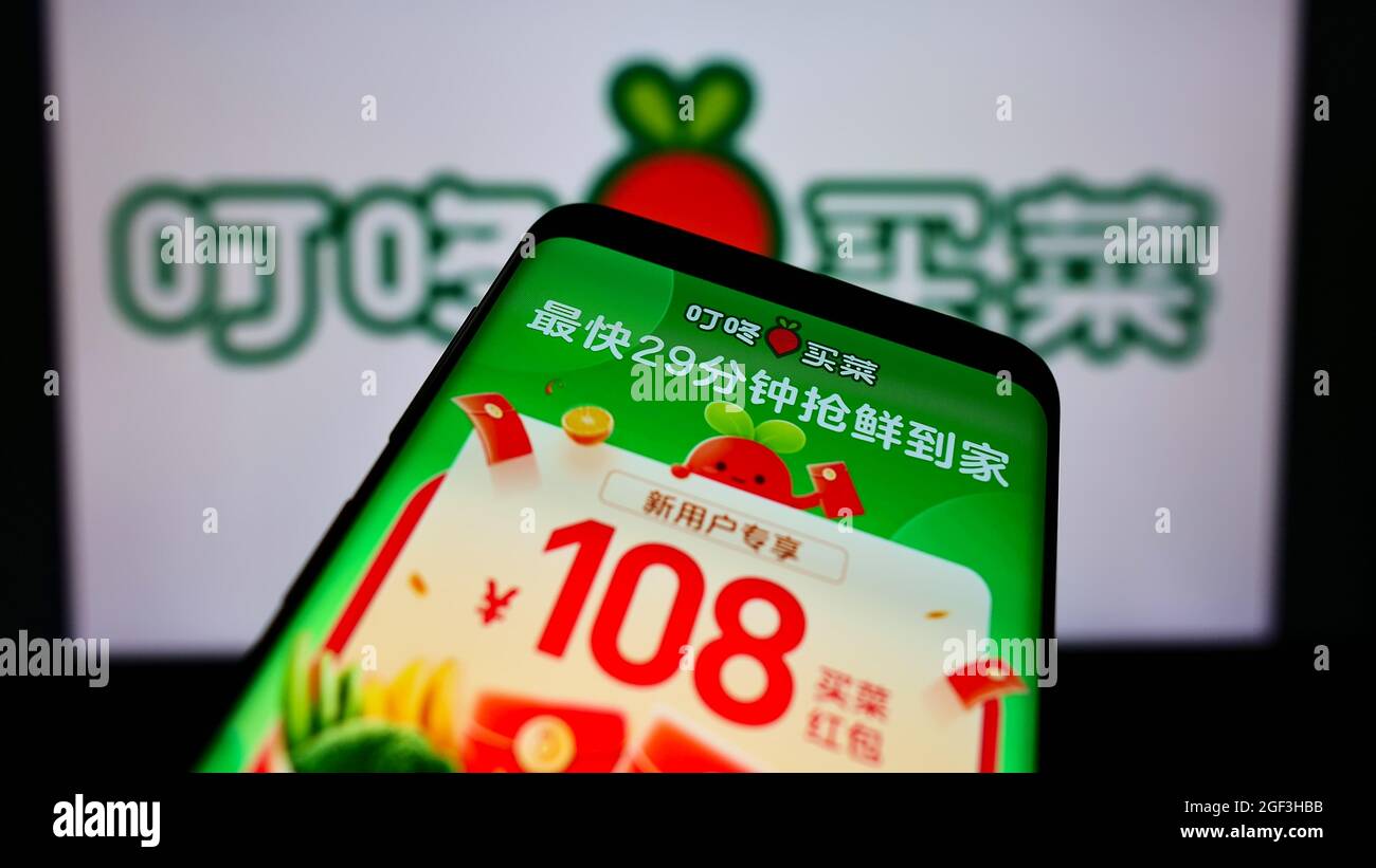 Telefono cellulare con pagina web della piattaforma cinese di e-commerce Dingdong Maicai sullo schermo di fronte al logo business. Mettere a fuoco sulla parte superiore sinistra del display del telefono. Foto Stock