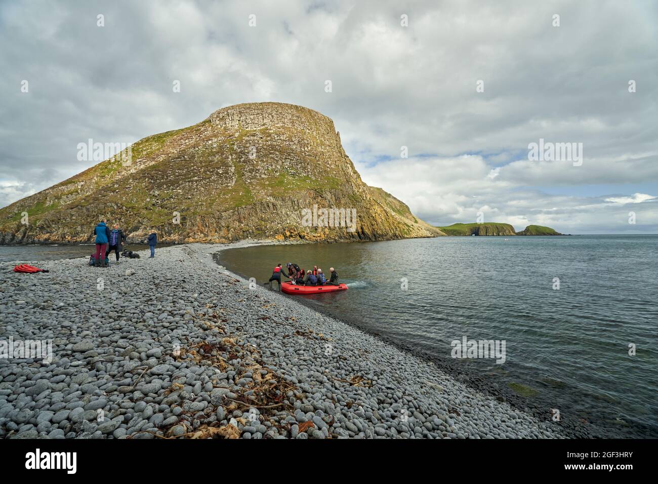 I visitatori in una gita di un giorno alle isole scianti che arrivano sull'istmo roccioso che unisce Garbh Eilean ed Eileen an Taighe. Foto Stock