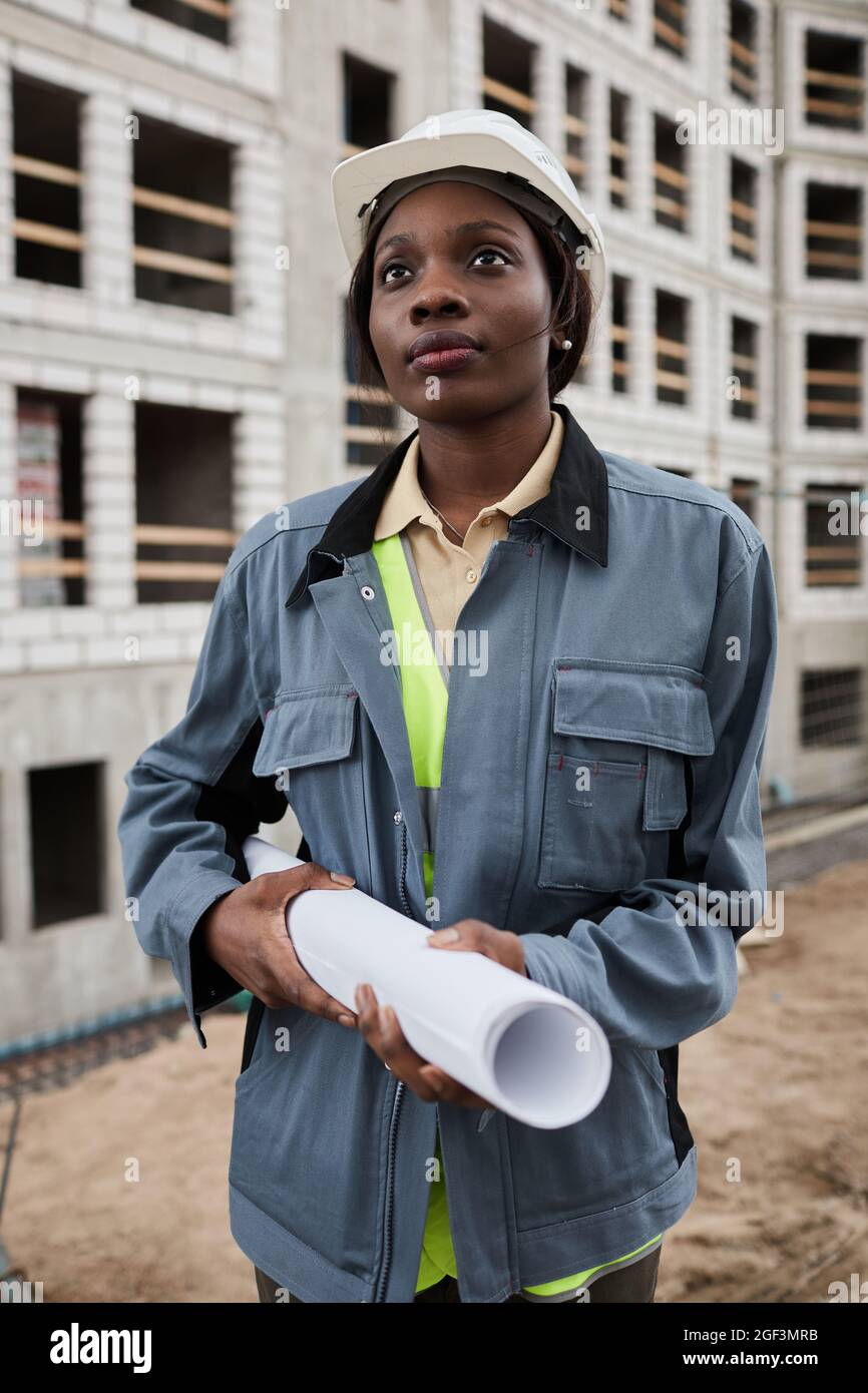 Ritratto verticale di giovane ingegnere femminile in posa in cantiere Foto Stock