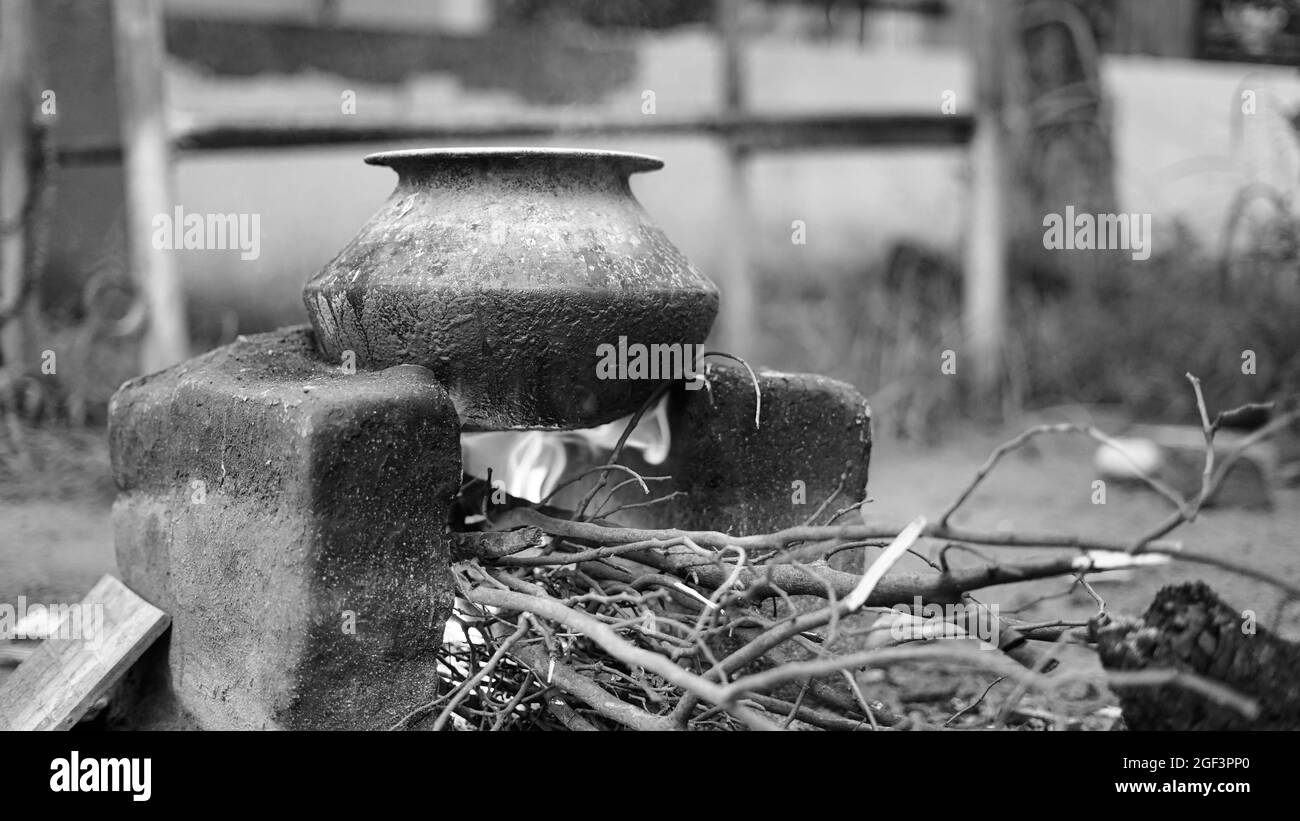 Colpo bianco e nero, stufa indiana di cottura del terreno all'aperto o stufa di campagna di Chulha o stufa di argilla con un vaso circolare di colore nero su esso, Foto Stock