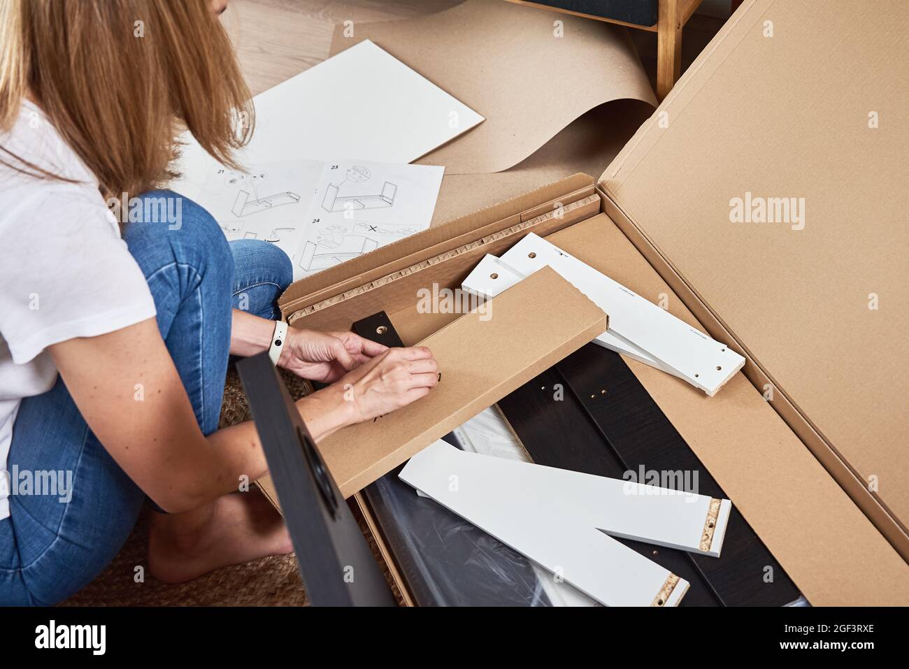 Donna che legge manuale istruzioni per assemblare mobili in soggiorno Foto Stock