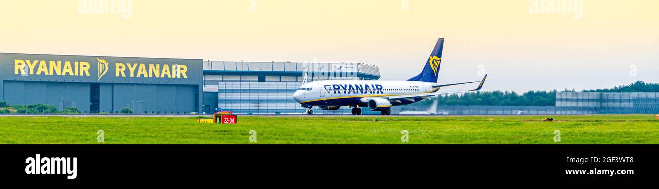 Ryan Air Ryanair Boeing 737 800 aereo jet decollo da Stansted Aeroporto Essex Inghilterra con il hangar di manutenzione in sfondo blu cielo giorno Foto Stock