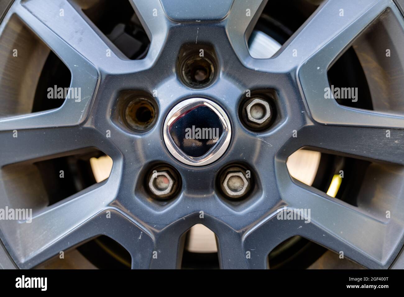 Una vista ravvicinata del cerchione e della ruota di una vettura con due dadi dentati rotti Foto Stock