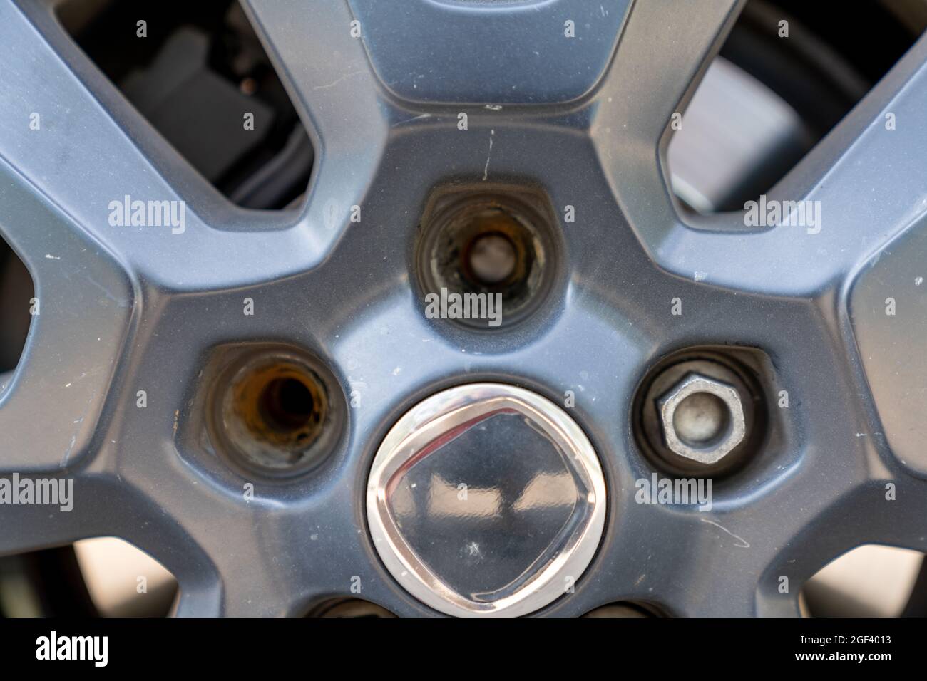 Una vista ravvicinata del cerchione e della ruota di una vettura con due dadi dentati rotti Foto Stock