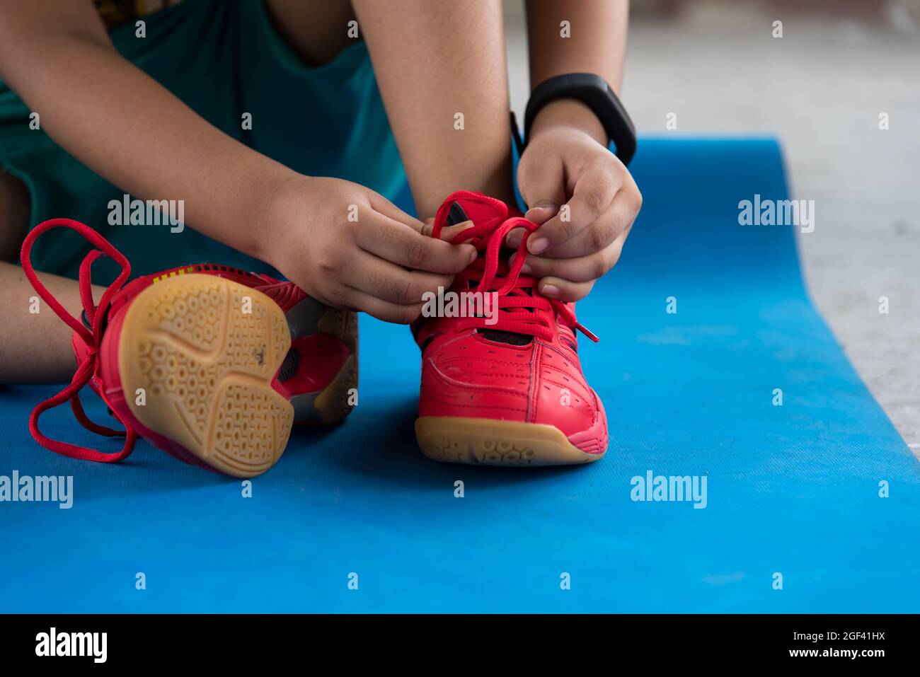 Un ragazzo che lega le scarpe da jogging che si prepara per un allenamento con l'uso di fuoco selettivo. Concetto di stile di vita sano Foto Stock