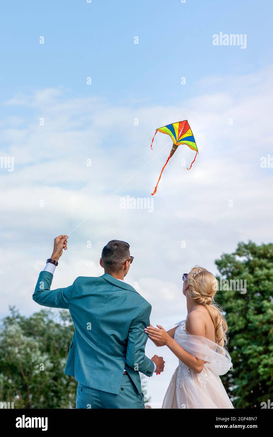 Un aquilone ad un matrimonio. Una coppia di nozze lancia un aquilone nel cielo. Sposi e sposi volano un aquilone insieme il loro giorno di nozze. Foto Stock