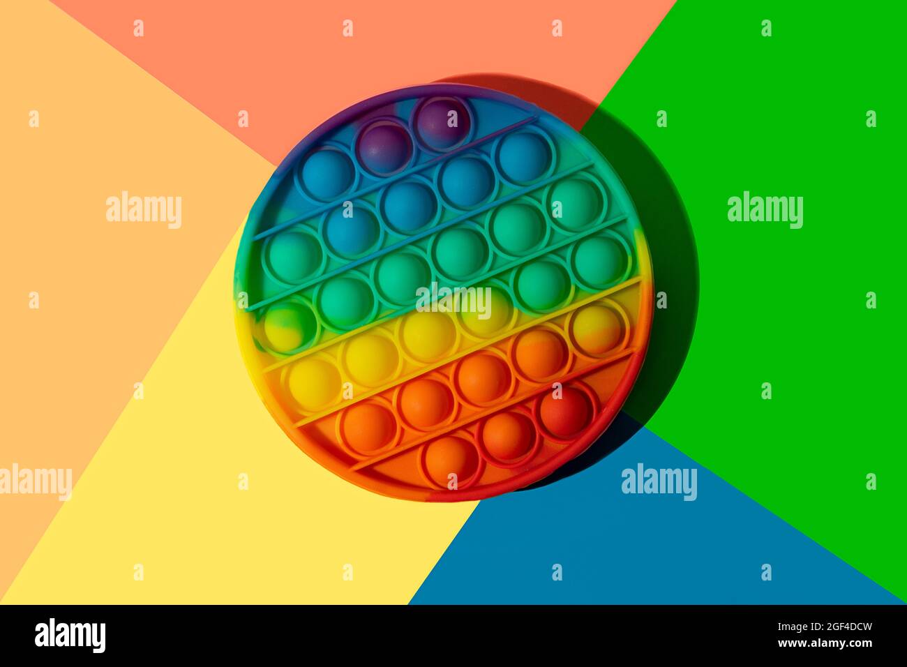 Il giocattolo antistress in silicone rotondo lo schioccano sullo sfondo colorato dell'arcobaleno. Foto Stock