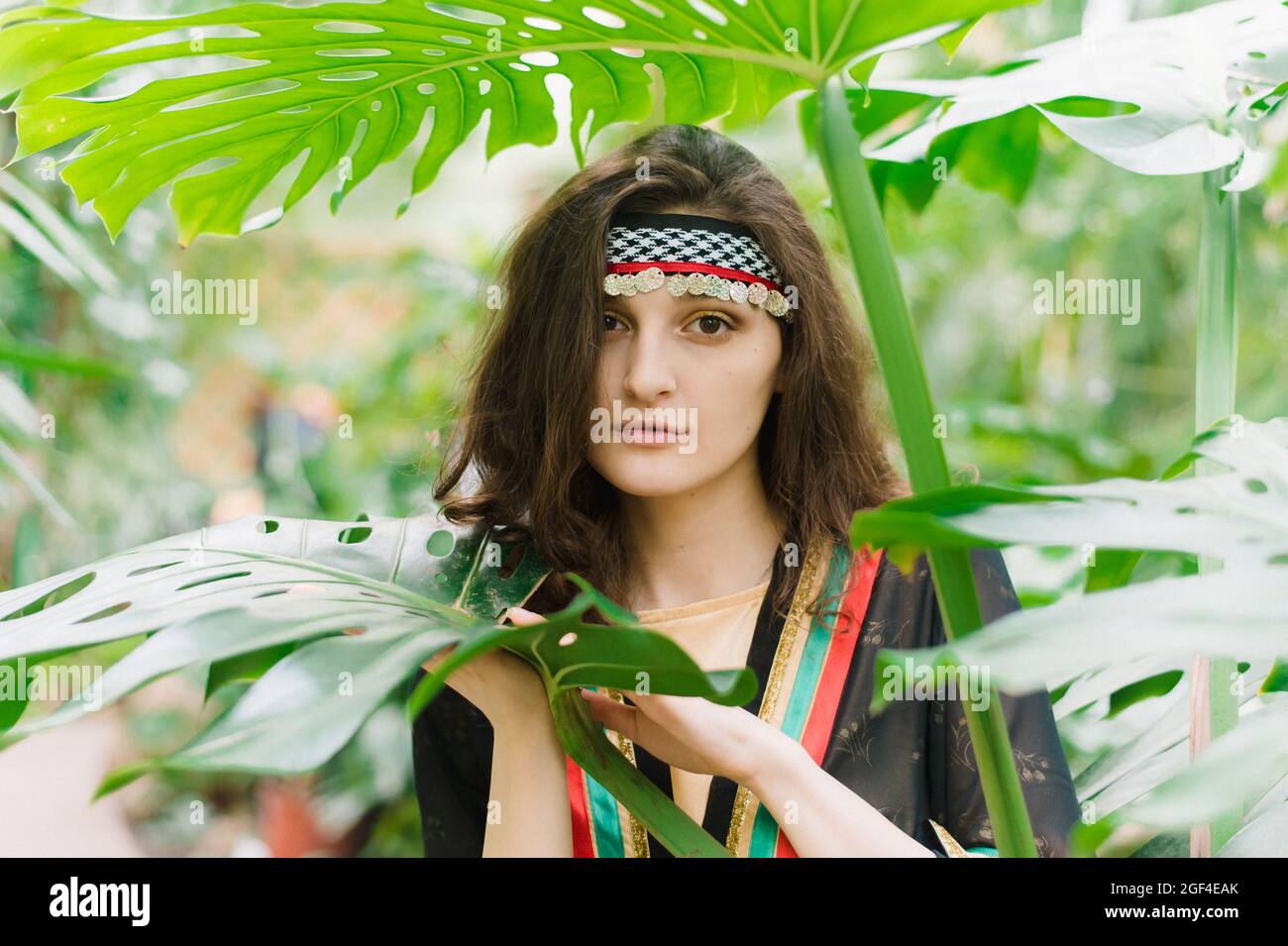 La ragazza dal Giordano sullo sfondo di piante e foglie di palmo. Ragazza giordana in costume nazionale di uno Stato arabo. Foto Stock