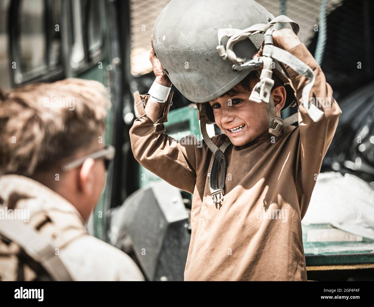 Una Marina statunitense assegnata alla Special Purpose Marine Air-Ground Task Force – Crisis Response – Central Command consegna un casco a un bambino in attesa di evacuazione all'Aeroporto Internazionale Hamid Karzai, Afghanistan, 22 agosto 2021. Gli Stati Uniti assistono il Dipartimento di Stato con un'operazione DI evacuazione non combatante (NEO) in Afghanistan. (STATI UNITI Foto del corpo marino di Gunnery Sgt. Melissa Marnellvia American PhotoArchive/Alamy) Foto Stock