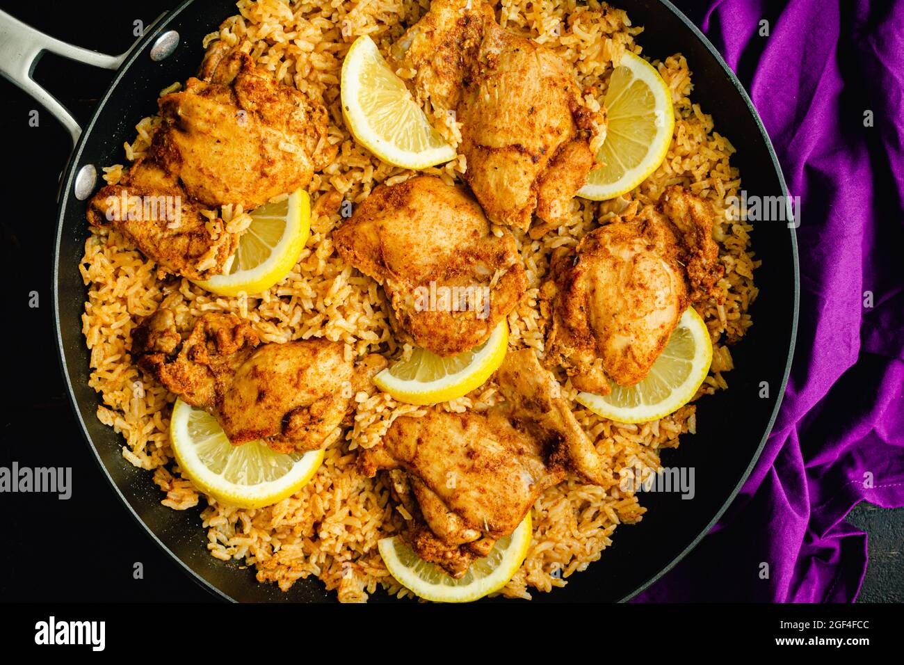 Una padella di pollo e riso spagnolo in una zattera: Cosce di pollo e riso condito con paprika affumicata, aglio e altre spezie Foto Stock