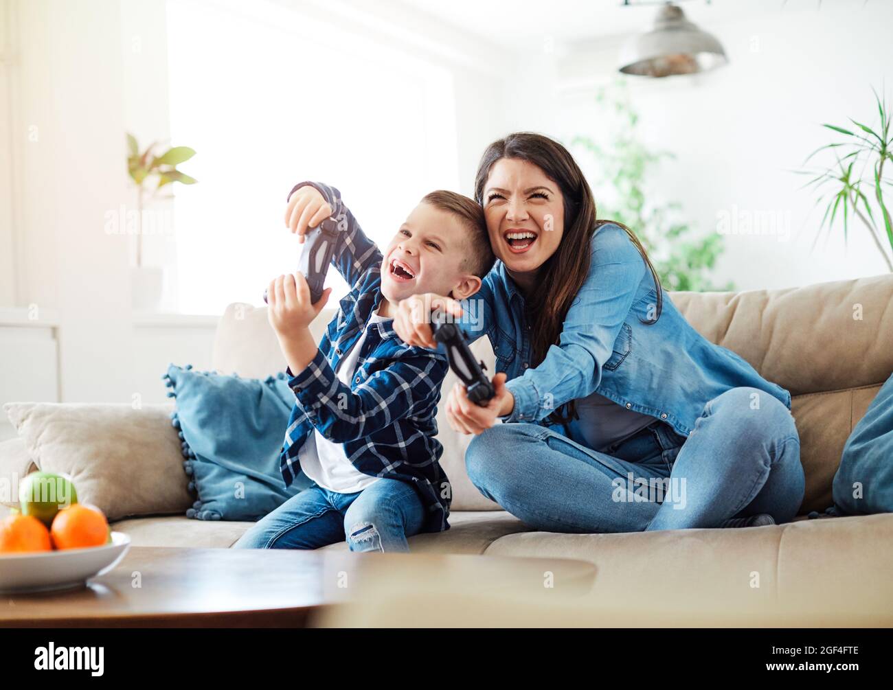 bambino figlio madre famiglia felice di giocare console bambino infanzia joystick cotterroller Foto Stock