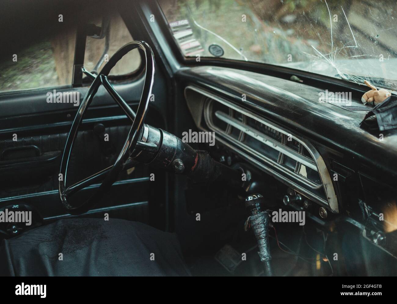 Primo piano dall'interno di un'auto d'epoca con parabrezza rotto Foto Stock