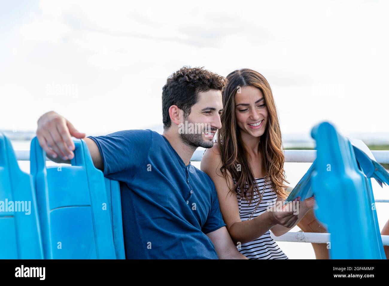 Sorridente coppia turistica che controlla la mappa mentre si siede in traghetto Foto Stock