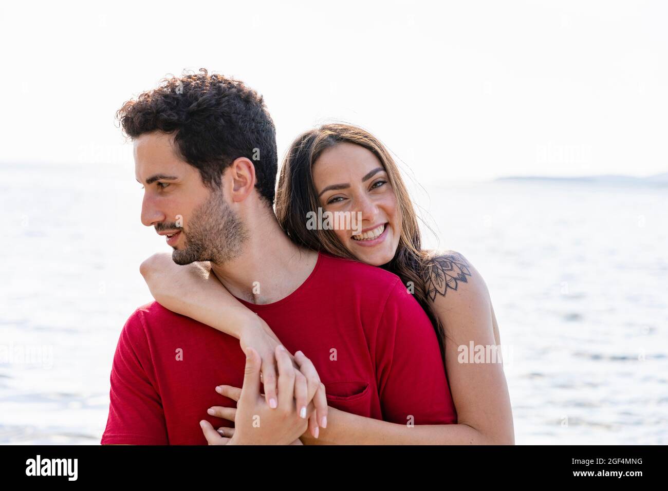 Donna sorridente che abbraccia l'uomo da dietro Foto Stock Donna sorridente che abbraccia l'uomo da dietro Foto Stock