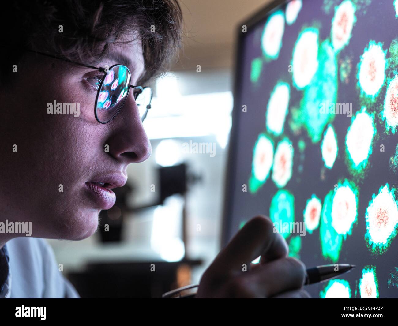 Scienziato maschile che ricerca su cellule biologiche su schermo di computer in laboratorio Foto Stock
