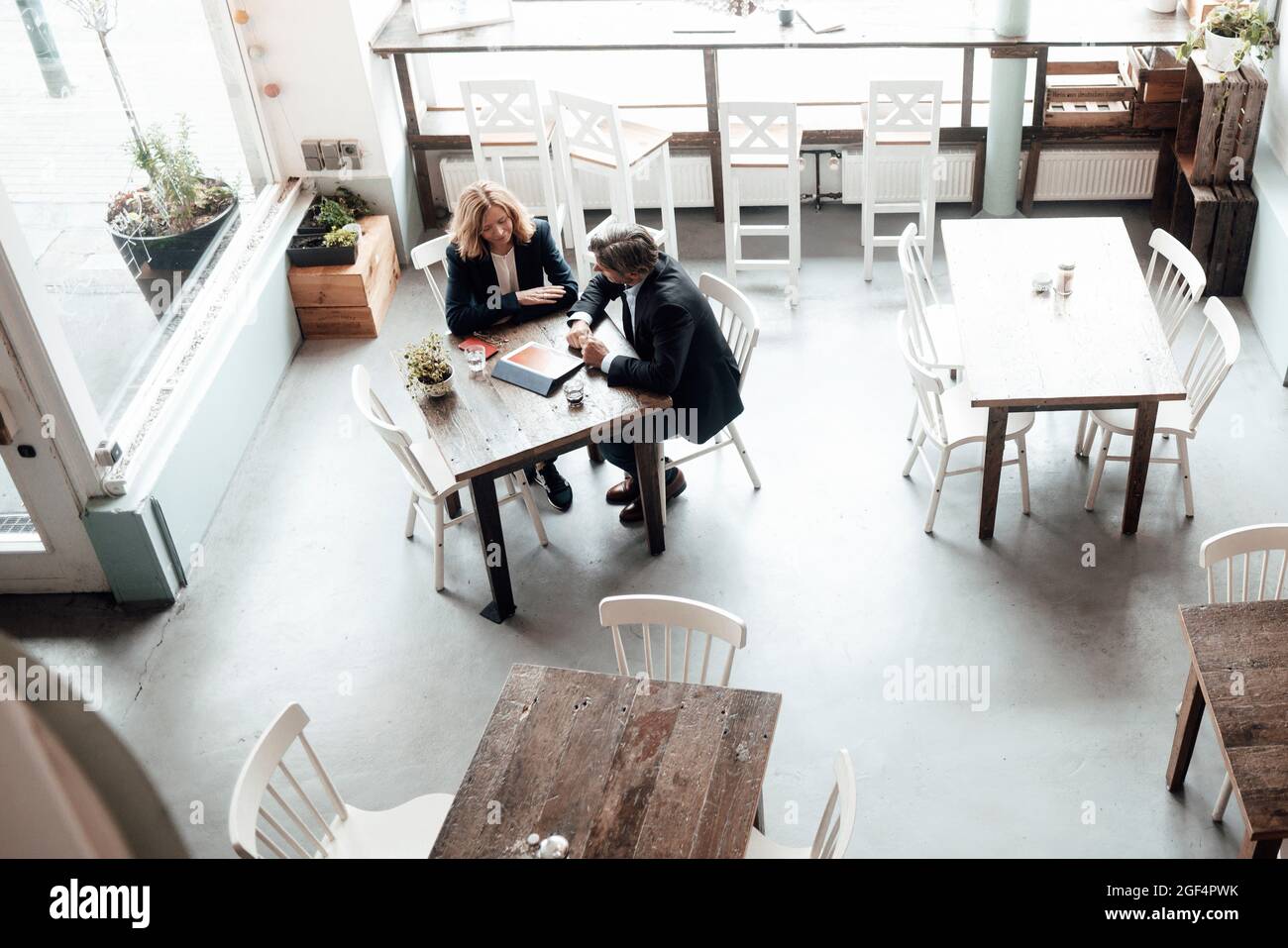 Professionisti di sesso maschile e femminile che condividono idee mentre discutono di tablet digitali in un bar Foto Stock