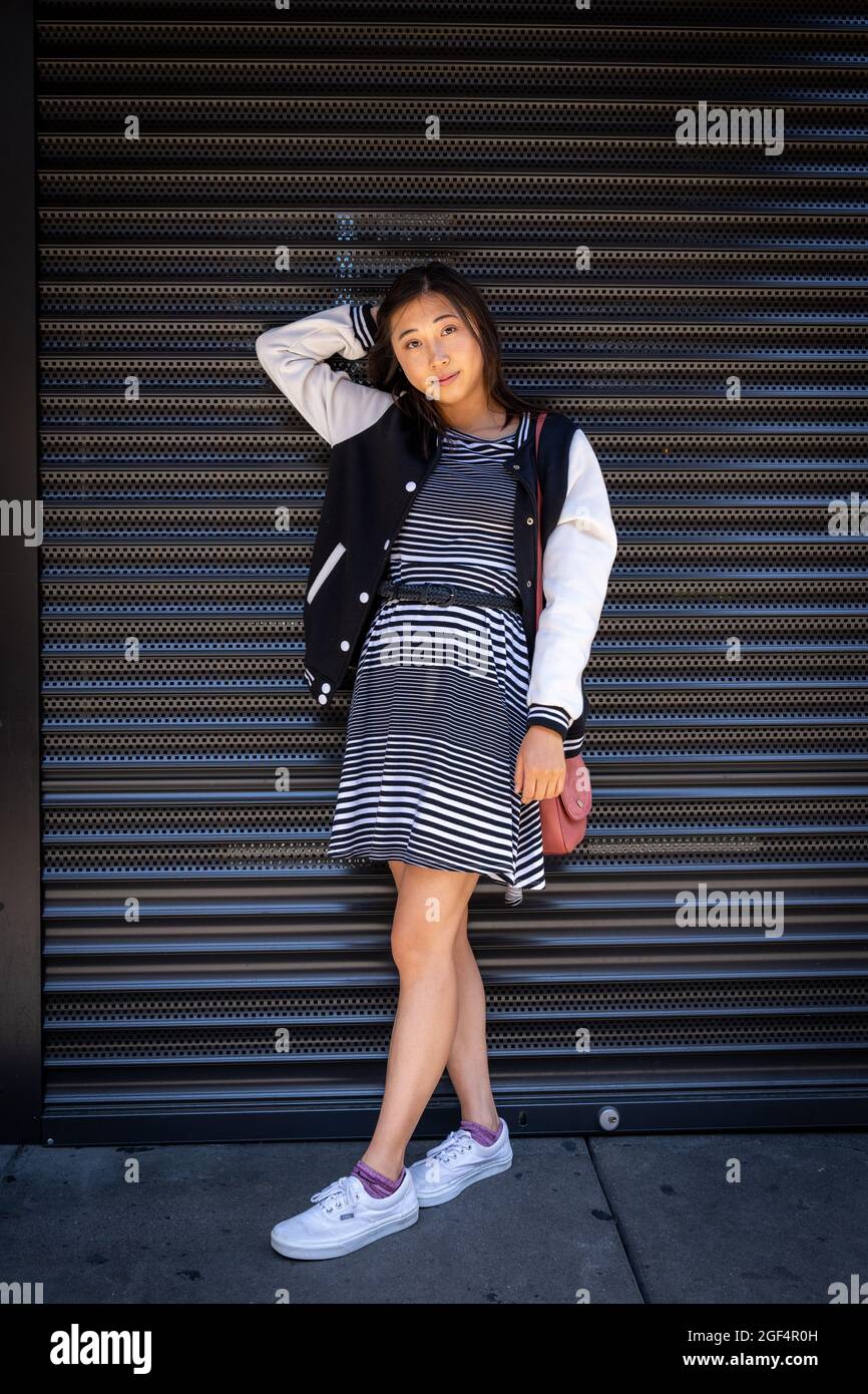 Ritratto di una bella giovane donna asiatica appoggiata su roll up porta di sicurezza in metallo a San Francisco Foto Stock