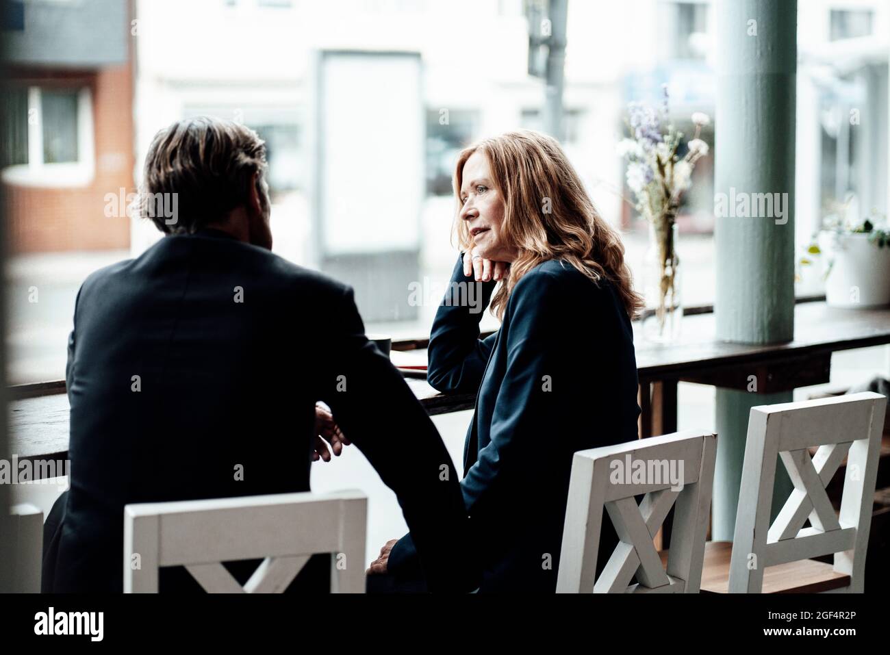 Senior bionda femminile professionale condividere idee durante la discussione con l'uomo d'affari in caffè Foto Stock