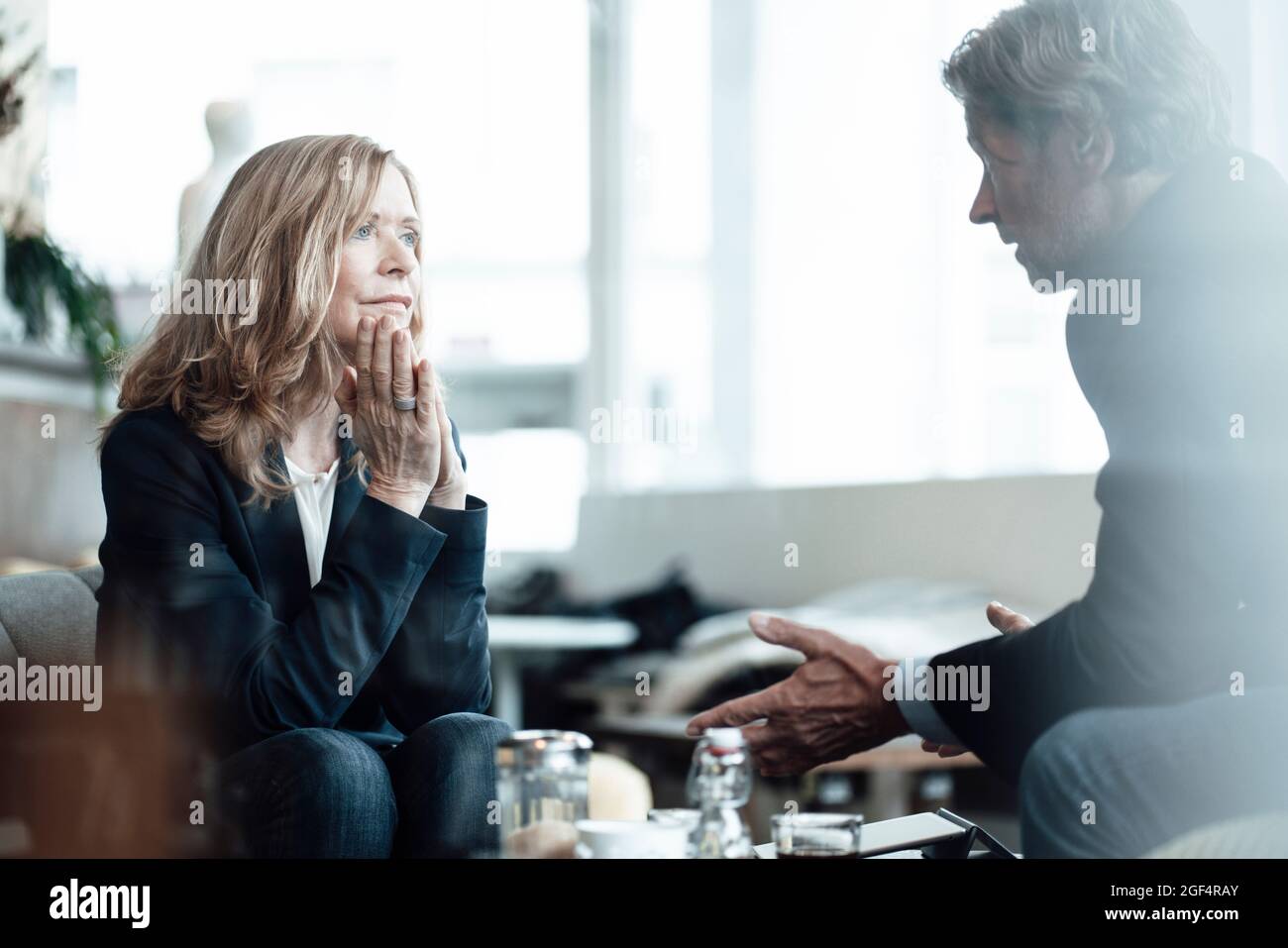Professionale femminile bionda anziana che guarda un collega maschio che condivide idee mentre discute in un bar Foto Stock