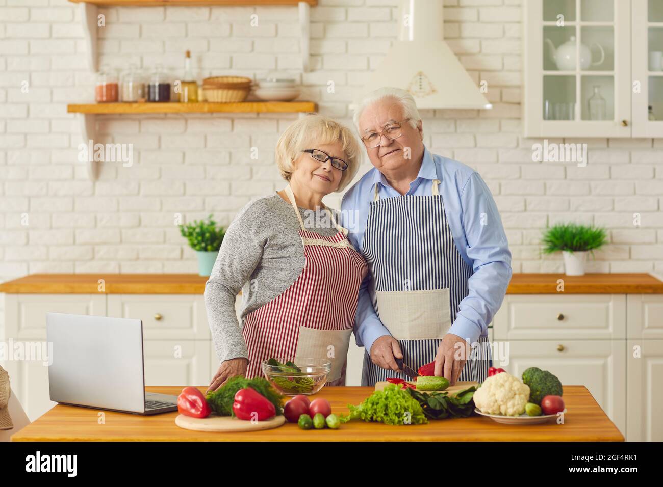 Ritratto di una coppia di anziani che cucinano cibo sano a casa con verdure biologiche. Foto Stock