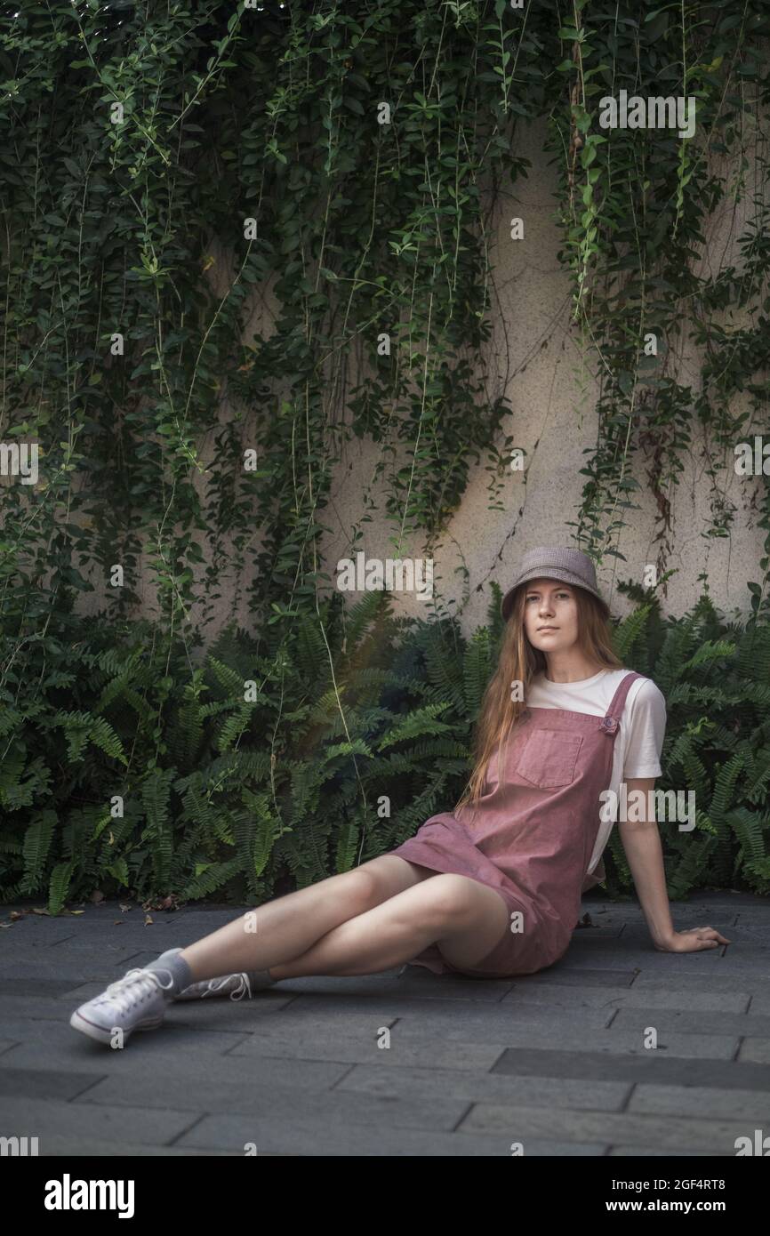 Bella donna caucasica con capelli biondi seduti sulla strada. Outfit alla moda casual estivo o primaverile. Foto di alta qualità Foto Stock