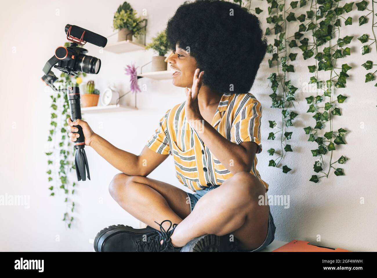 Il giovane influencer afro vacilla mentre vlogging attraverso la fotocamera a casa Foto Stock