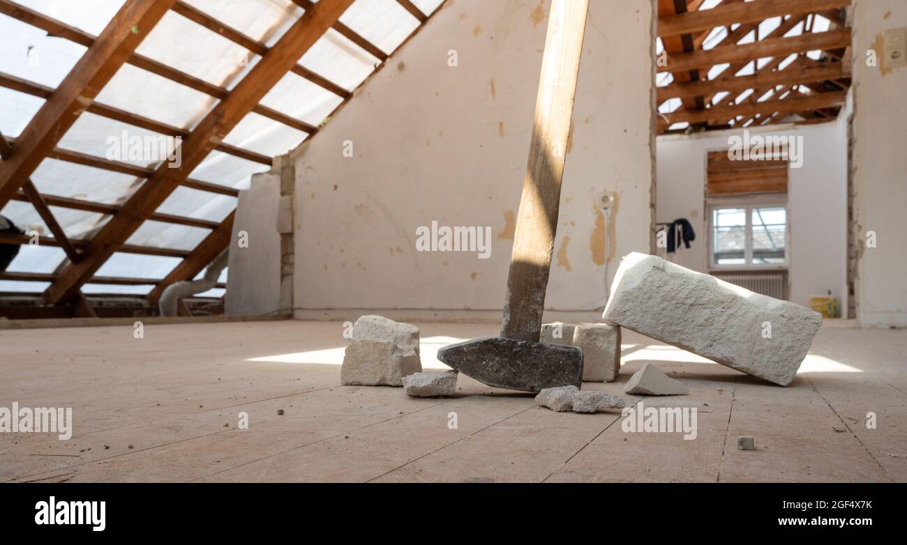 Ristrutturando la mansarda di una casa privata. Sul pavimento giacciono un martello da slitta e alcuni mattoni. Foto Stock