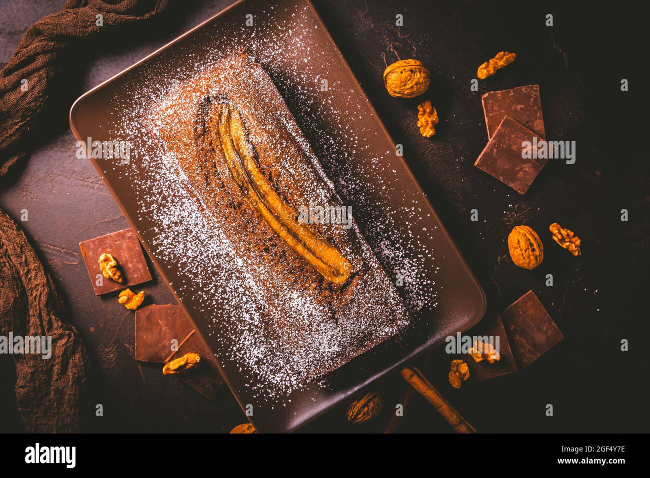 Pane di banana vegano fatto in casa o torta con noci, cioccolato e cannella su sfondo marrone Foto Stock