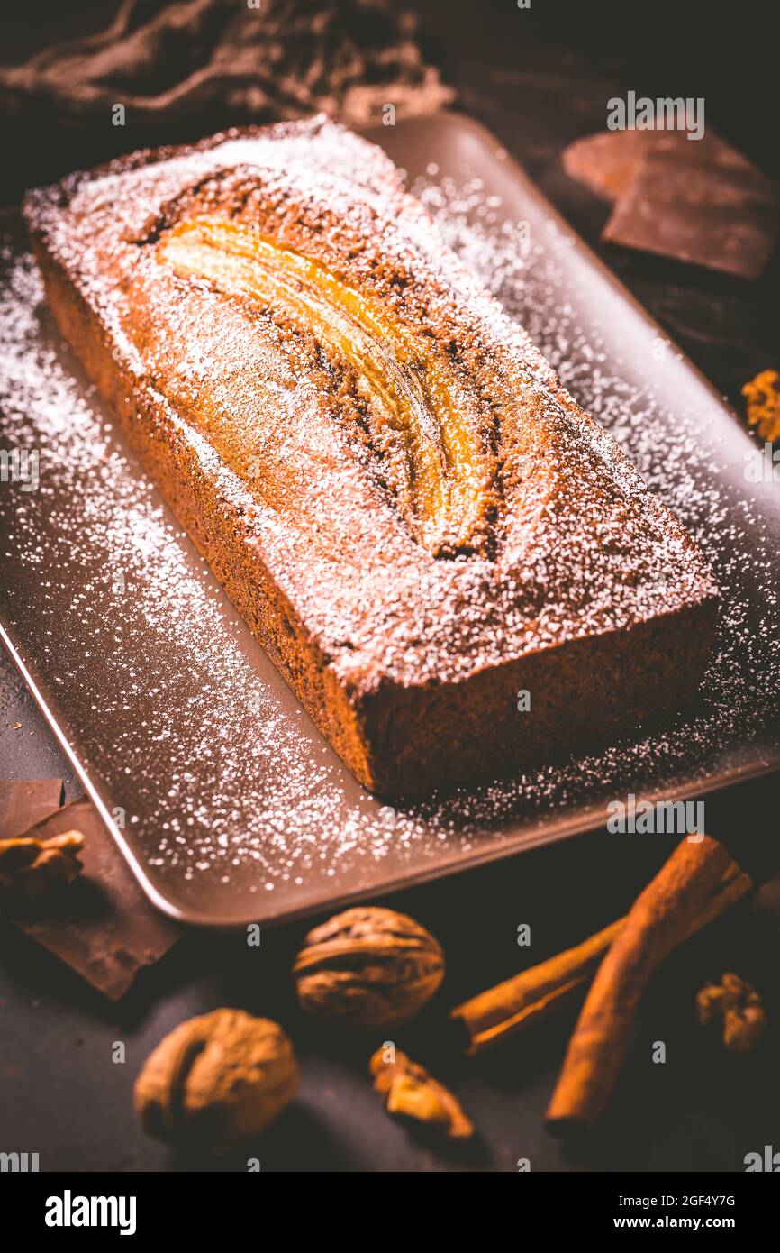 Pane di banana vegano fatto in casa o torta con noci, cioccolato e cannella su sfondo marrone Foto Stock