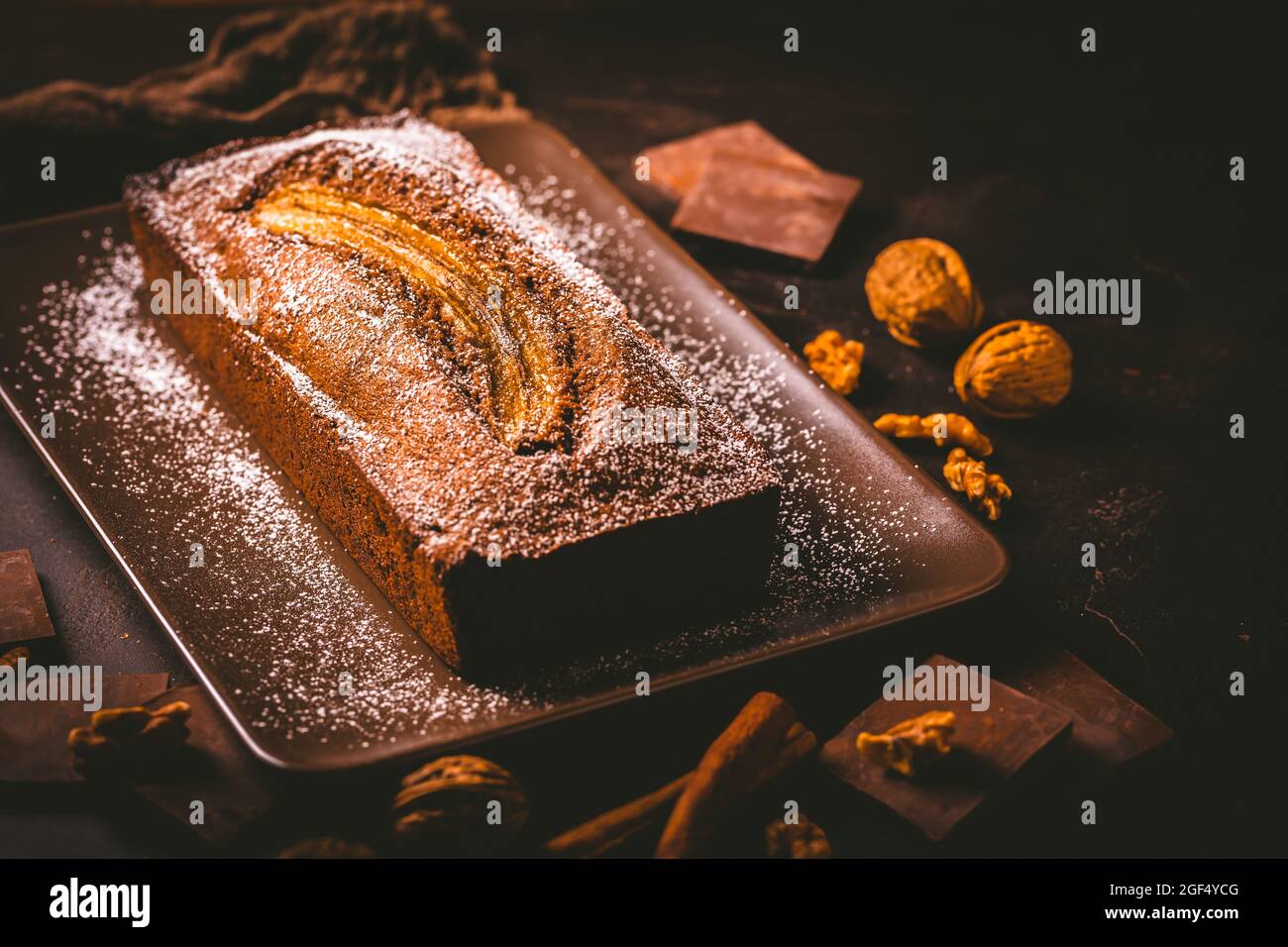 Pane di banana vegano fatto in casa o torta con noci, cioccolato e cannella su sfondo marrone Foto Stock