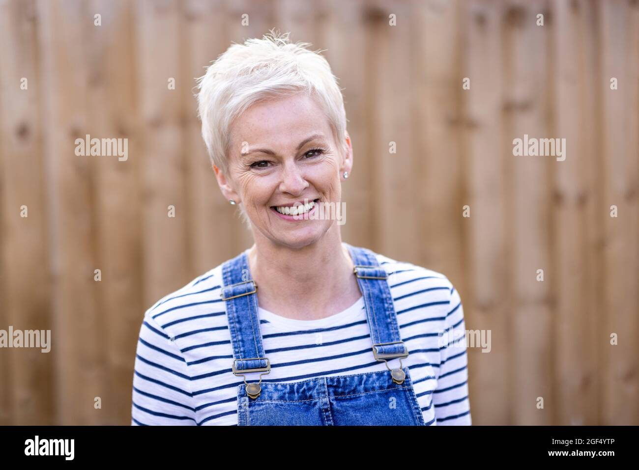 Donna matura con capelli corti sorridenti al cortile Foto Stock