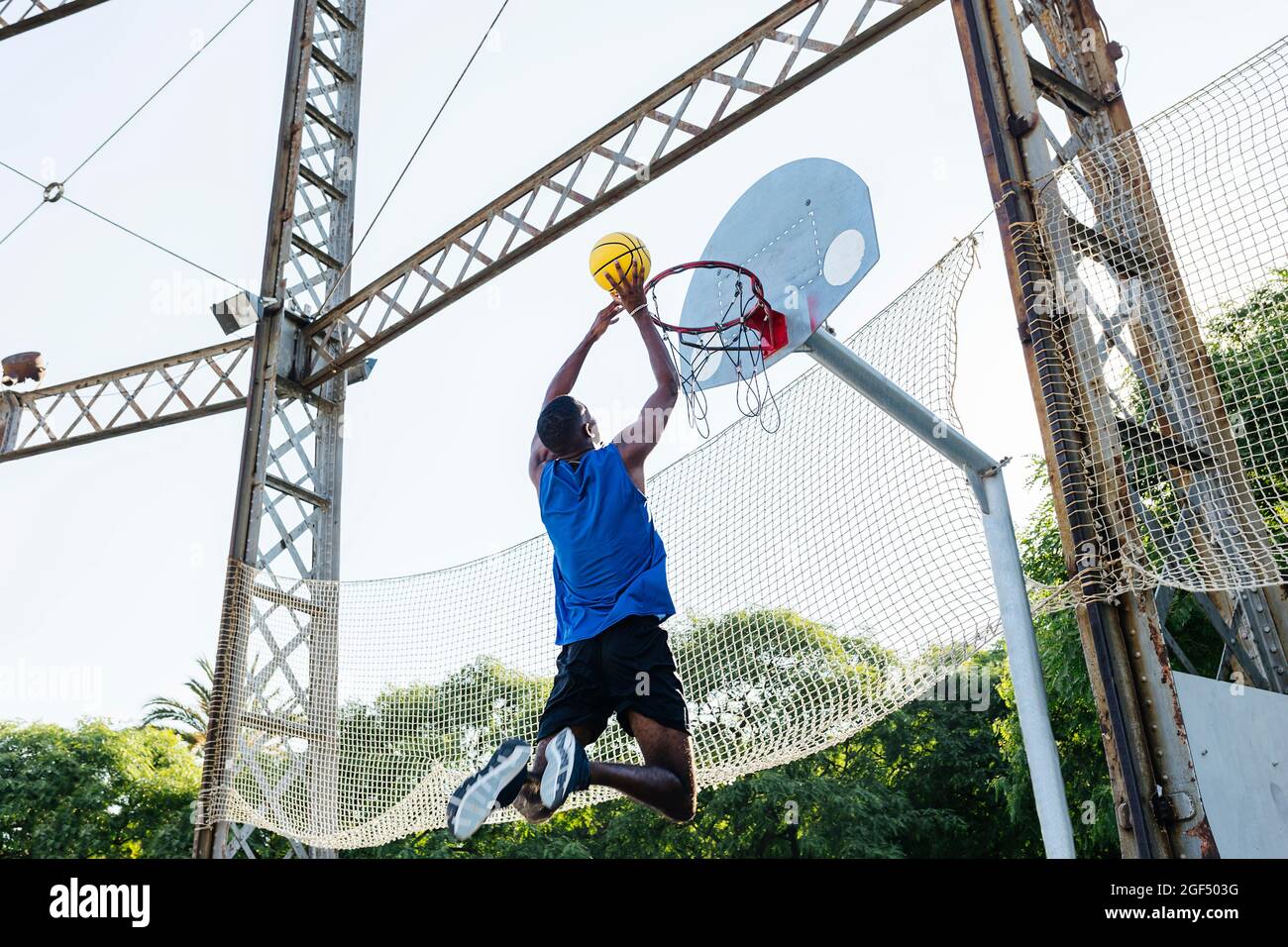Giovane uomo che cimenta nel basket mentre gioca al campo sportivo Foto Stock