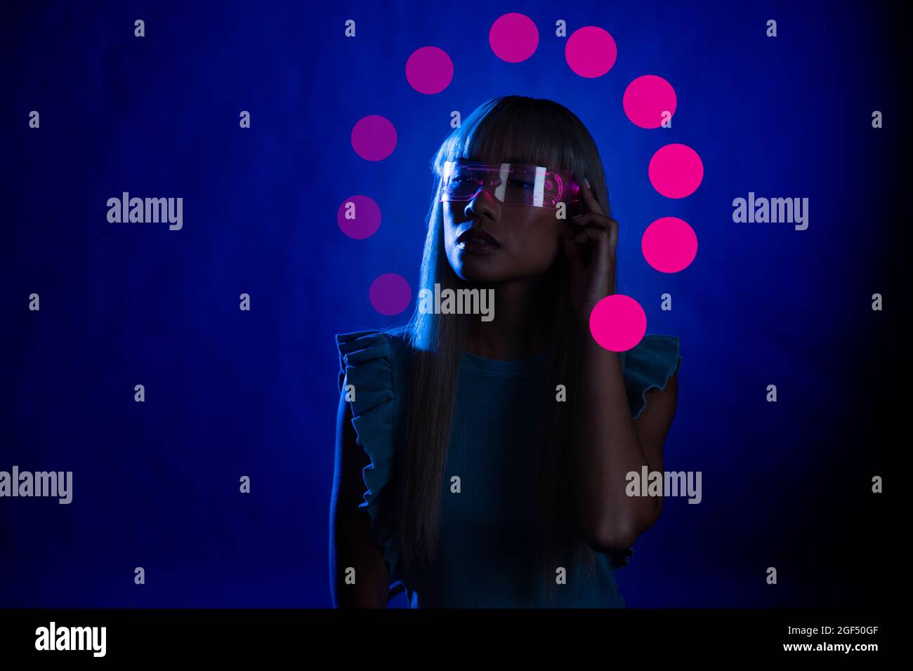 Giovane donna che indossa occhiali eleganti su sfondo blu Foto Stock