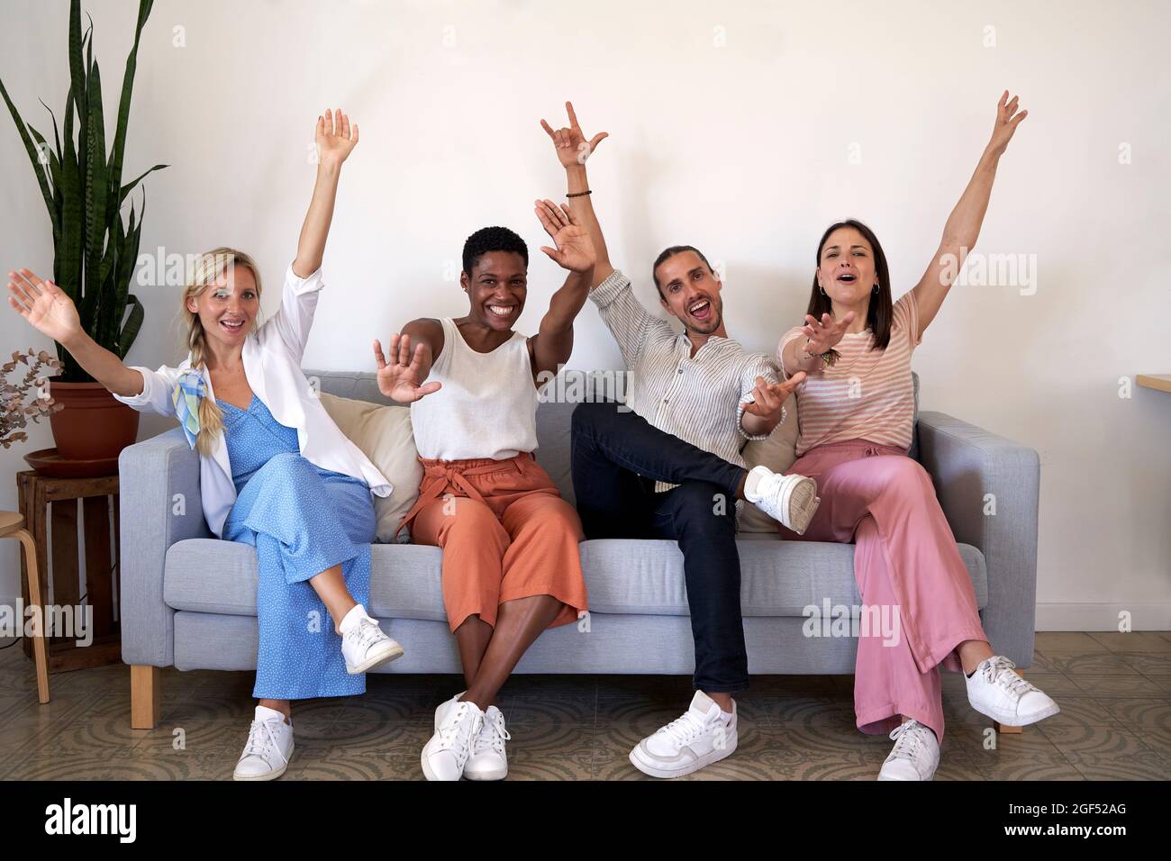 Colleghi maschi e femmine che si acclamano mentre si siedono sul divano Foto Stock