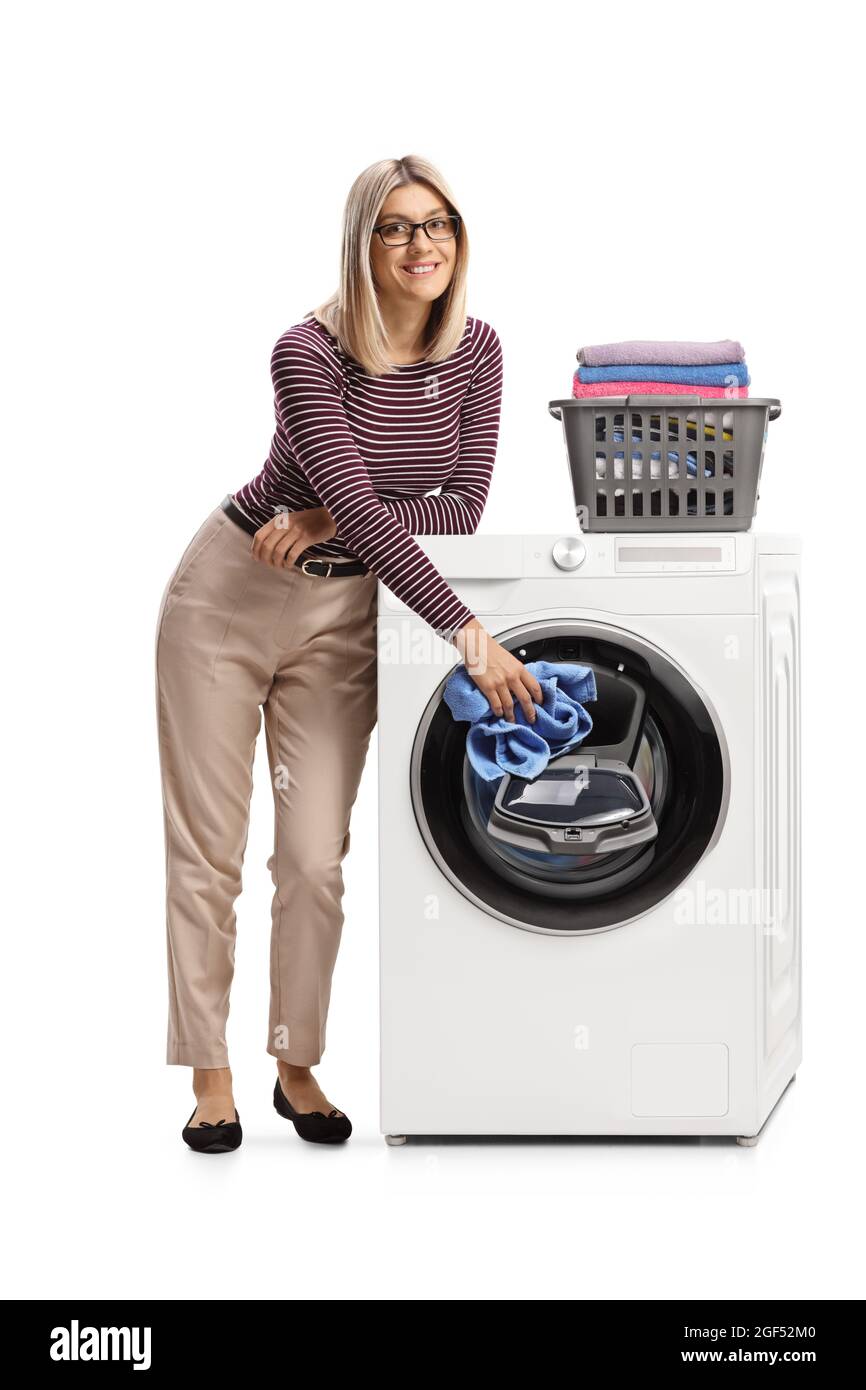 Ritratto a tutta lunghezza di una donna appoggiata su una lavatrice e aggiungendo abiti isolati su sfondo bianco Foto Stock
