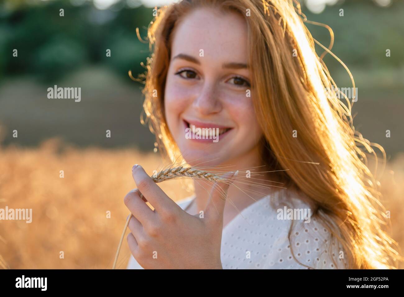 Bella donna che tiene orecchio di grano sorridente il giorno di sole Foto Stock