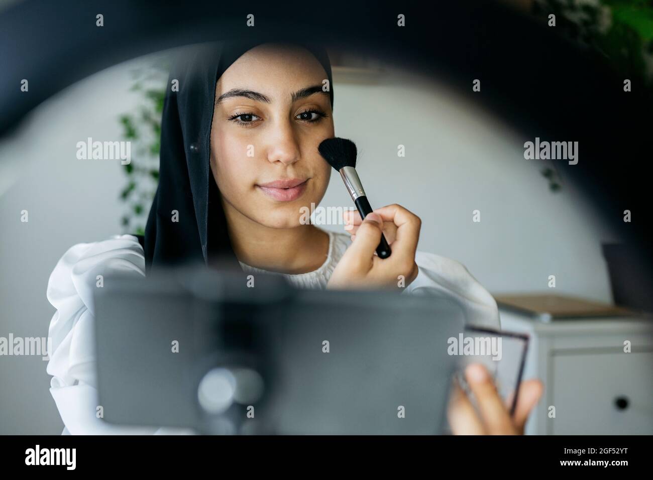 Vlogger femmina che fa il make-up tutorial a casa Foto Stock